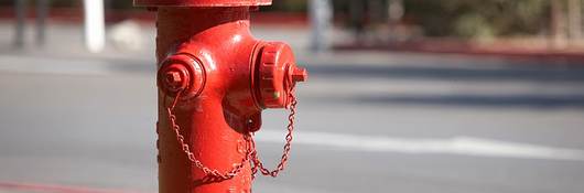 A bright red fire hydrant along a road.