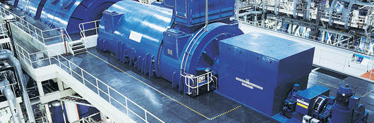 Two workers near an industrial generator in a warehouse setting