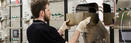 Man using a bank of small testing chambers to determine VOC emissions from products.