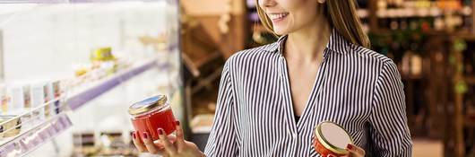 A woman in the supermarket studies a candle made with sustainable palm oil.