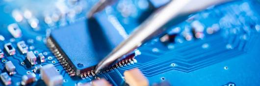 A pair of specialized tweezers places a circuit on a board