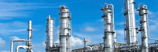 Energy processing facility against a blue sky with drifting clouds