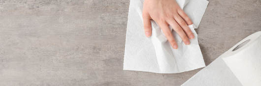 Woman wipes counter with a white paper towel. 