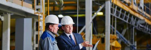 Two men in warehouse looking at laptop