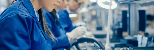 Female electronics factory workers in protective glasses assembling printed circuit boards 