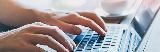 Photo of a man typing on a laptop keyboard