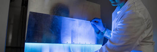 A woman uses UV light to inactivate harmful material on products.