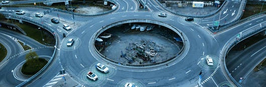 Autonomous self-driving cars moving in a traffic circle next to a highway. 