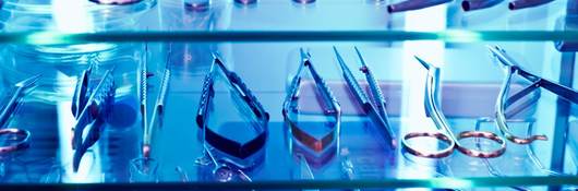 An array of medical devices sit within a cabinet basking in UV light.