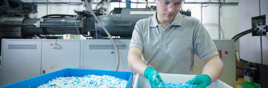 Worker inspecting recycled plastic in plastics factory