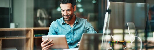 Smiling man looking at tablet in an office workspace