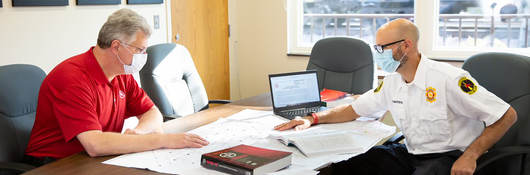 Two code authorities sitting at a table together looking at building plans.