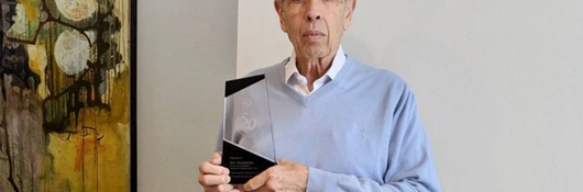 Image of Dov Glucksman holding his commemorative award for 50-years of loyalty.