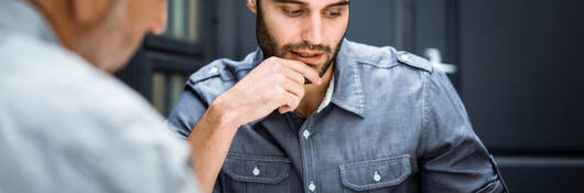 Two male business professionals reviewing documentation at workplace.