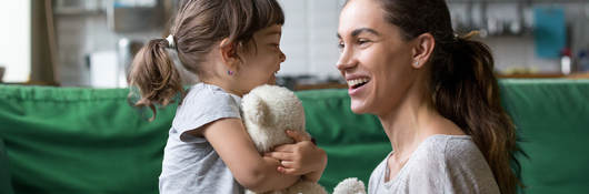 A mother plays in the living room with her child