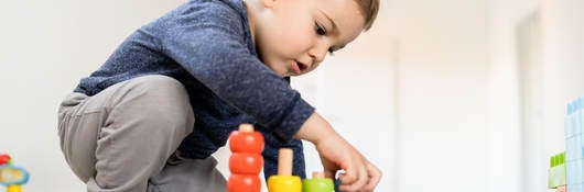 Small boy playing with little wood toys at home on the floor learning colors and counting