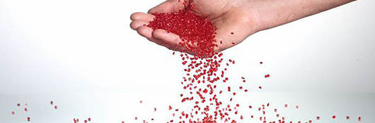 A hand catching red plastic pellets