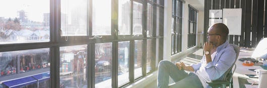 Man sitting in office looking out window. 