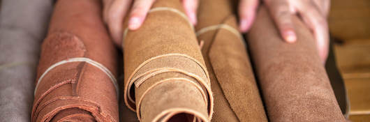 A pair of hands holds rolled leather sheets
