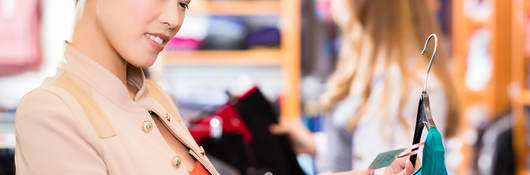 Woman checking tag on clothing in a retail shop