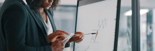 Shot of a young businessman and businesswoman using an interactive whiteboard to analyse data in a modern office