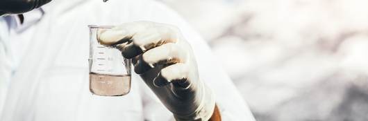 Person in protective suit examining polluted water