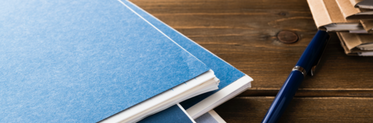 Notebooks and pen on a wooden table