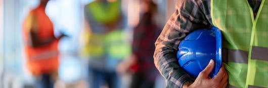 Man holding blue hard hat while on the job at warehouse