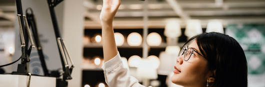 A consumer examines a row of lamps at a retail store.