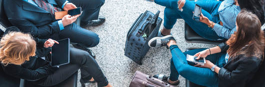 Passengers using mobile devices while waiting at an airport