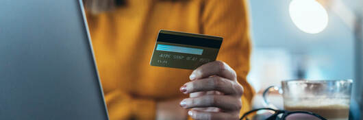 woman holding a credit card and sitting in front of a laptop computer