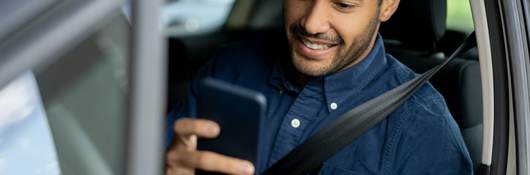 man looking at a mobile phone in car