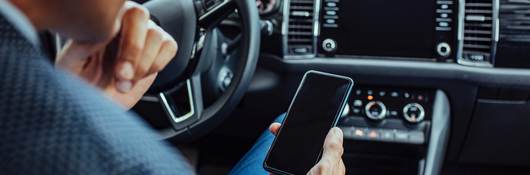 man looking at a mobile phone in car