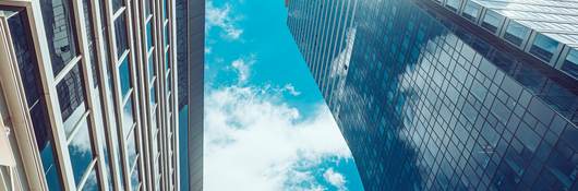 sky with clouds peeking through tall buildings