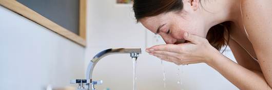 Person washing their face over a sink