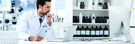 A doctor operates a computer in a laboratory setting.