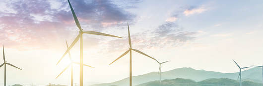 Wind farm on hillside with sunset in background