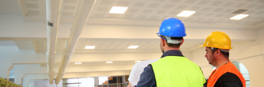 Construction workers looking at blueprints inside construction site.