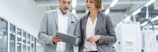 Workmates walking and discussing a subject while looking at a tablet