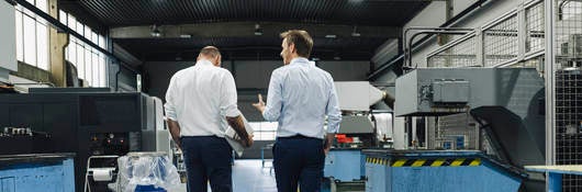 Two men walking and talking in a factory