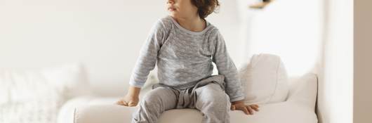 Child in pajamas sitting on a couch
