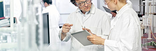 Two scientists working on a tablet in a lab