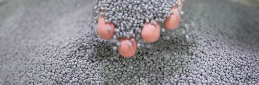 A person's hand holding plastic pellets