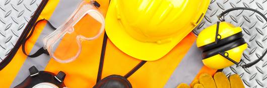 Industrial protective workwear shot from above on diamond-plate background. Includes hard hat, safety glasses, earmuff, gloves, respiratory mask, steel toe shoes and safety vest.