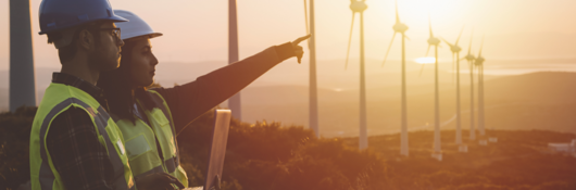 Maintenance engineer team working in wind turbine farm at sunset