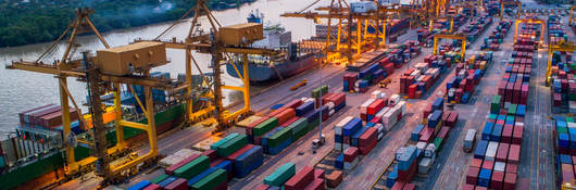 Container cargo ship and cargo plane with working crane bridge in shipyard at sunrise