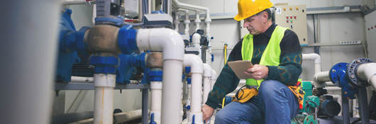 Senior repairman in boiler room checking pipes