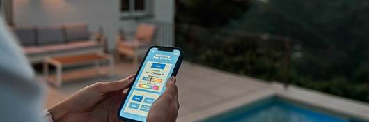 A homeowner uses her mobile device to control the lighting settings of her pool.