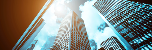 looking up through modern office buildings seeing sun streaming in