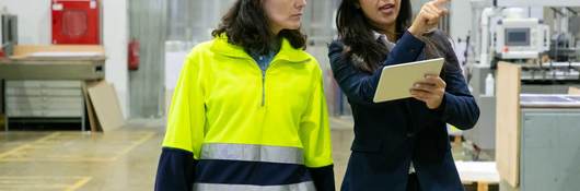 Female plant manager with tablet and middle-aged woman in hardhat